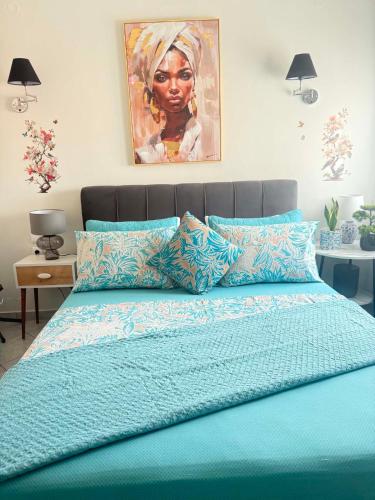 a bedroom with a blue bed with a painting on the wall at 7th sky Aristotelous in Thessaloniki