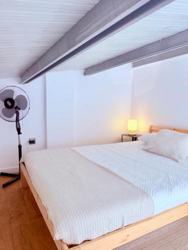 a bedroom with a large white bed and a lamp at Bam’s Farm in Alcobaça