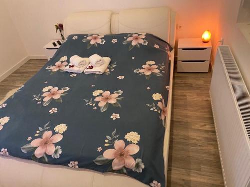 a bed with a blanket with flowers on it at SPA apartman in Kragujevac