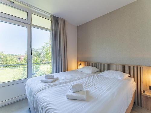 a bedroom with a large white bed with two towels on it at Coastal Escape w Sauna in Zoutelande