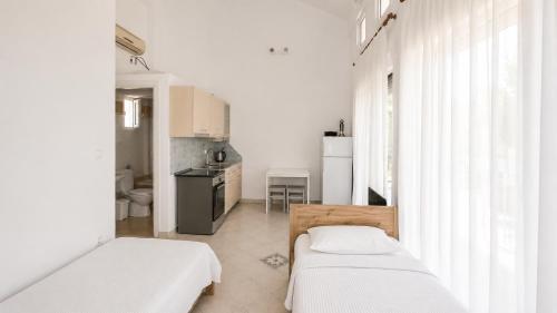 a room with two beds and a kitchen with white walls at Villa Elena in Ormos Panagias