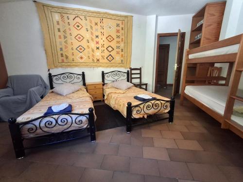 a room with two beds and a chair in it at Setcases-Vallter hostal Mitja Pensió 2 in Setcases