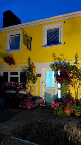 a yellow house with flowers in front of it at Globe Guesthouse in Burry Port