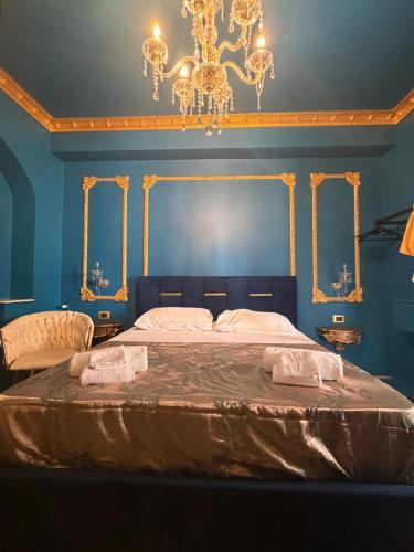 a blue bedroom with a large bed with a chandelier at XVI Secolo House in Scalea