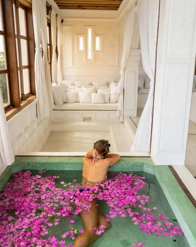 a woman laying in a pool filled with pink flowers at Kilele House in Lamu