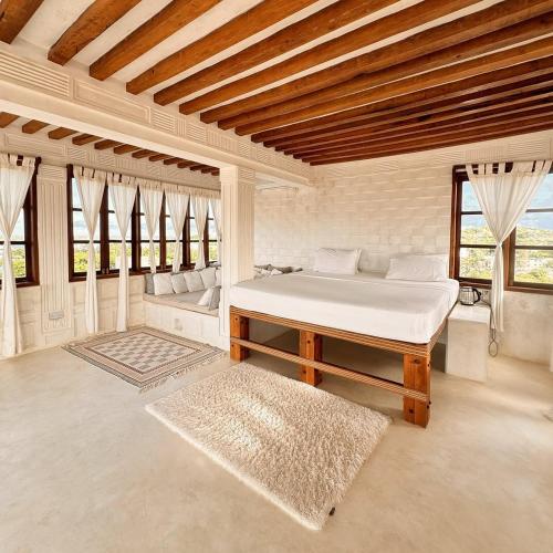 a bedroom with a bed and a couch and windows at Kilele House in Lamu