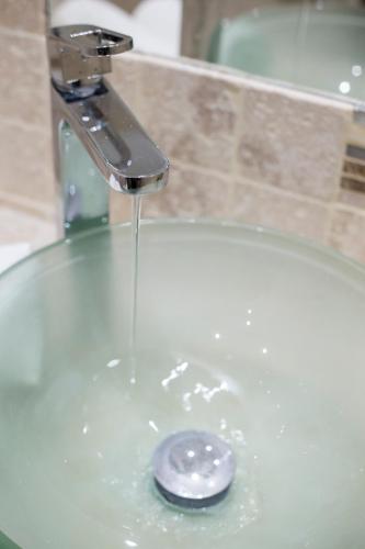 un lavabo de salle de bain avec de l'eau qui coule d'un robinet dans l'établissement Le Carré D'Or by Connexion, à Cannes