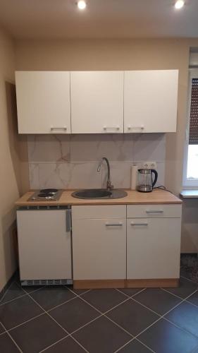 a kitchen with white cabinets and a sink at Gästezimmer Heinebach in Alheim