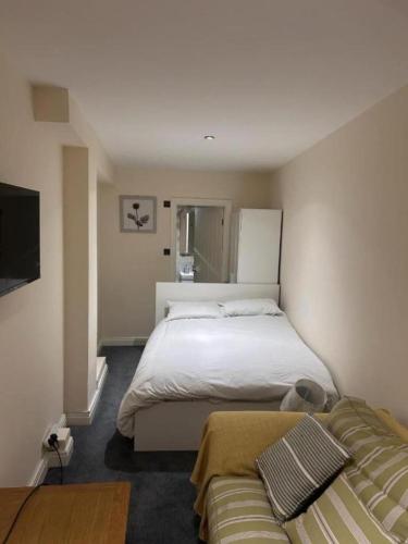 a bedroom with a large bed and a couch at Quiet Double Room Ensuite Marble Bathroom South Croydon in Croydon