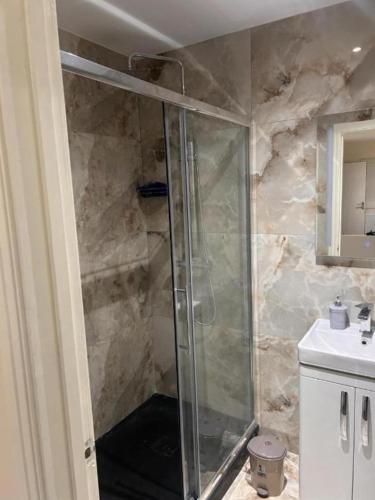 a shower with a glass door in a bathroom at Quiet Double Room Ensuite Marble Bathroom South Croydon in Croydon