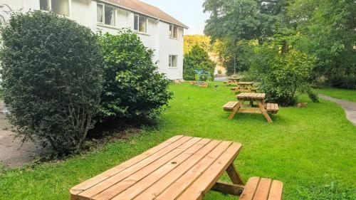 a row of wooden picnic tables in the grass at Parkside Lodge Hotel in Camelford