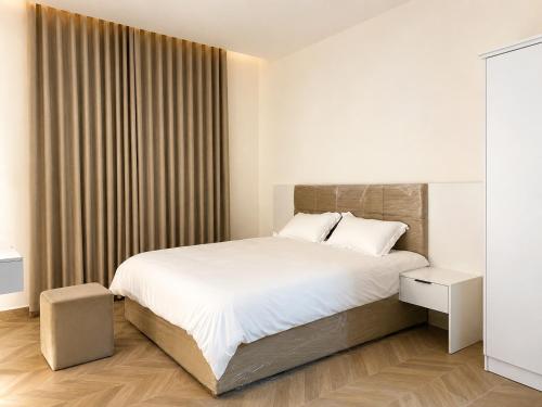 a white bedroom with a large bed and a window at Bin Fhaid Suites in Salalah