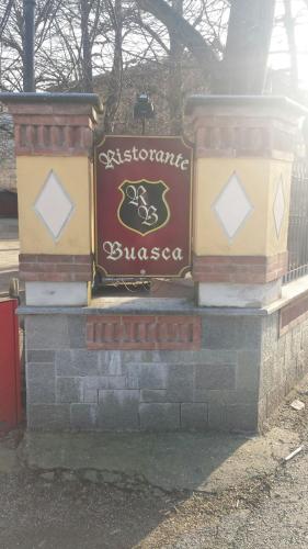a sign for a restaurant on a brick wall at Ristorante Buasca in Cuorgnè