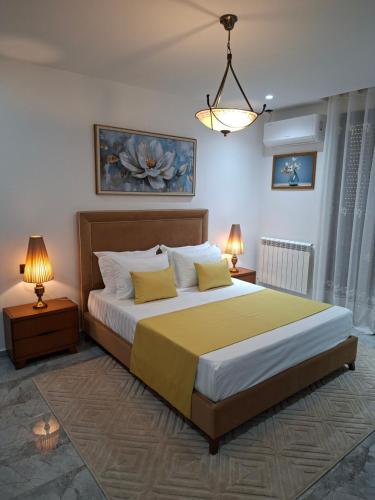a bedroom with a large bed with two night stands and two lamps at Bel appartement in Cheraga