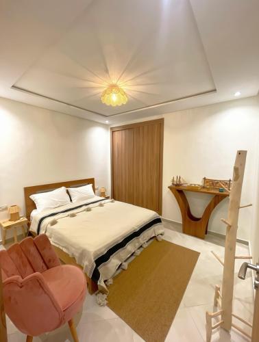 a bedroom with a bed and a chair and a table at 2BR Pool View Kids Pool & Gym 6 Min to Beach in Dar Hamida