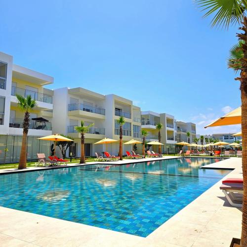 a swimming pool in front of a building with palm trees at 2BR Pool View Kids Pool & Gym 6 Min to Beach in Dar Hamida