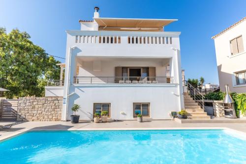 a villa with a swimming pool in front of a house at Villa Gagra - Villa by the Sea with a Private Pool in Panormos Rethymno