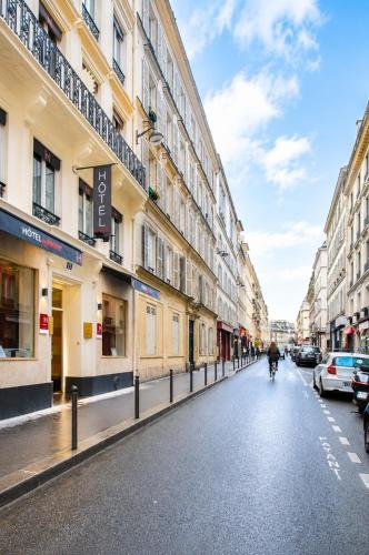 a person riding a bike down a street with buildings at Hotel Migny Opéra Montmartre in Paris