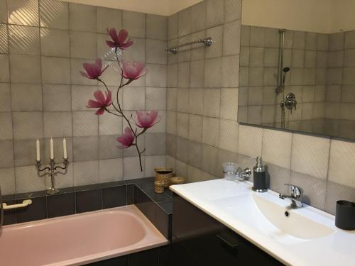 a bathroom with a sink and a tub and pink flowers at Residenza al Volto in Venice