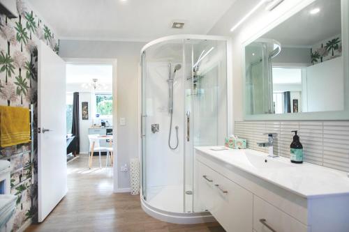 a white bathroom with a shower and a sink at Waikanae Beach Suite Retreat in Waikanae
