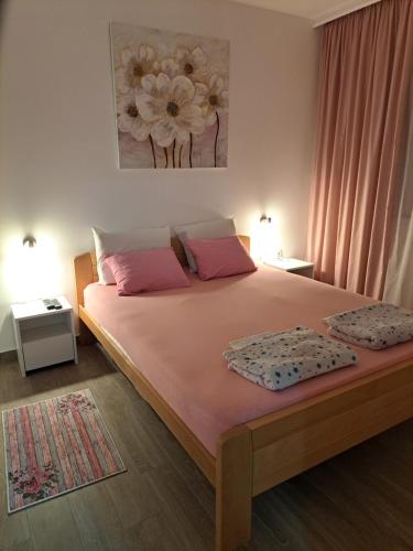 a bedroom with a large bed with pink pillows at Apartman Jass in Stari Banovci