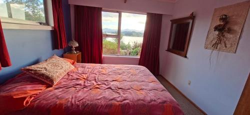 a bedroom with a bed with a red comforter and a window at Pureanei in Rawene
