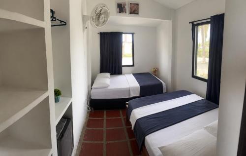 a small room with two beds and a window at Hotel Mar del Viento in San Bernardo del Viento