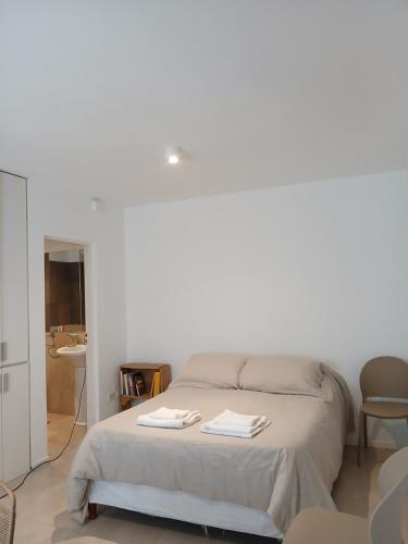 a white bedroom with a bed with two towels on it at Punto Sur Apart in Río Cuarto