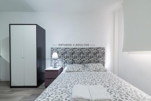 Habitación blanca con cama y espejo en Apartamentos Arapiles, en Madrid