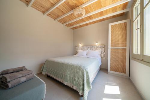 a bedroom with a white bed and a wooden ceiling at Meraki Seaside Suite Pelion in Kalamos