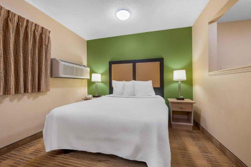 a bedroom with a white bed and green walls at Extended Stay America Suites - Chicago - O'Hare - Allstate Arena in Des Plaines