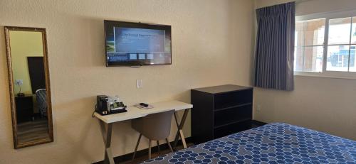 a hotel room with a bed and a television on the wall at Grapevine Inn in Lodi