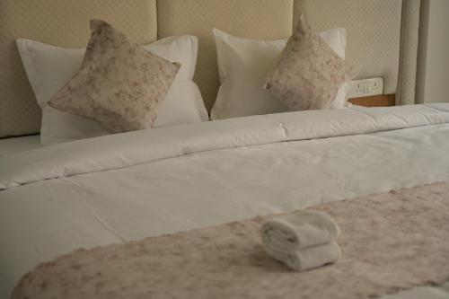 a bed with white pillows and a white blanket at Hotel Surya Inn in Patna