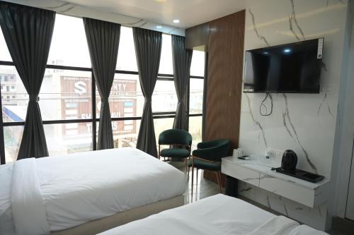 a hotel room with two beds and a flat screen tv at Hotel Surya Inn in Patna