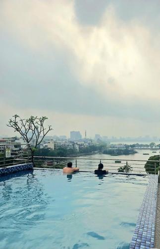 two people sitting in a swimming pool overlooking a river at LP Hotel & Spa Pham Hong Thai in Hanoi
