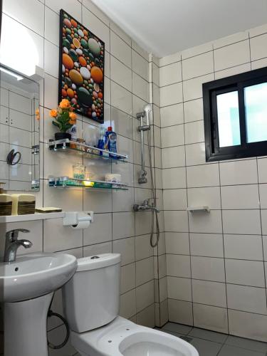 a white bathroom with a toilet and a sink at La pépite de Joelle in Douala