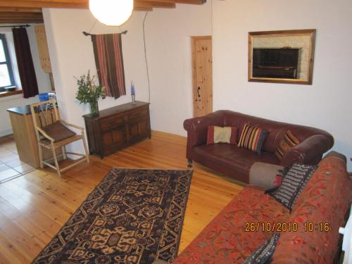 a living room with a leather couch and a rug at Shiplake Mountain Farmhouse in Dunmanway