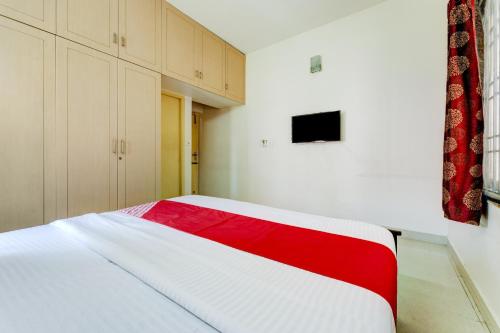 a bedroom with a red and white bed in it at Hotel O J2 Service Apartment in Chennai