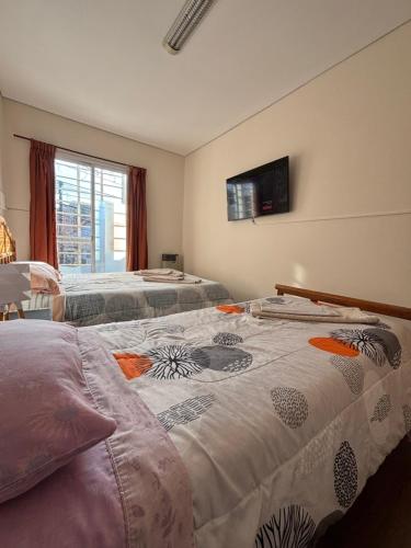 a bedroom with two beds and a tv on the wall at KAD Alojamiento in Mendoza