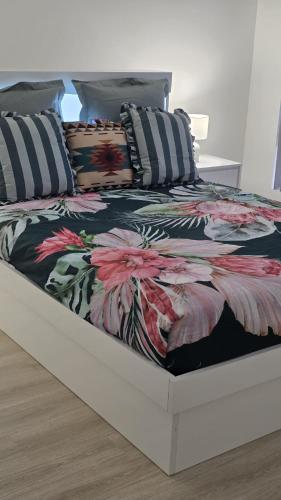 a bed with a floral comforter and pillows on it at Seahawk Escape in Mandurah