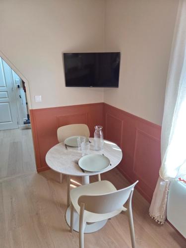 a small table with two chairs and a tv on a wall at L'Appart Millésime - Escapade champenoise Épernay in Magenta