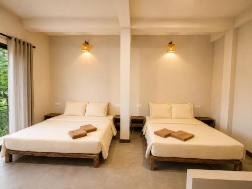 two beds in a room with two lamps at Ella Brown House in Ella