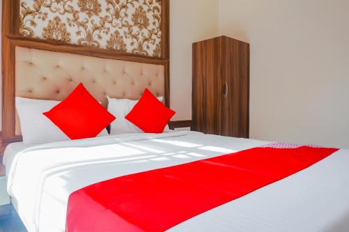 a bedroom with a large white bed with red pillows at Hotel O Rest Inn in Yeraoda