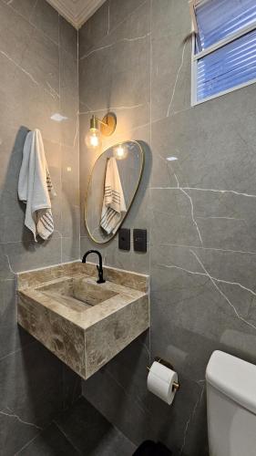 a bathroom with a sink and a mirror at Casa com 3 suítes e piscina privativa no centro de Maragogi perto da praia in Maragogi