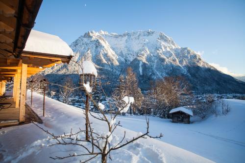 a snow covered mountain in front of a cabin at Gröbl-Alm in Mittenwald