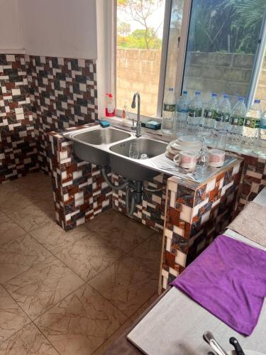 a kitchen with a sink and a counter with water bottles at Baraka Nema Villa Resorts in Gunjur