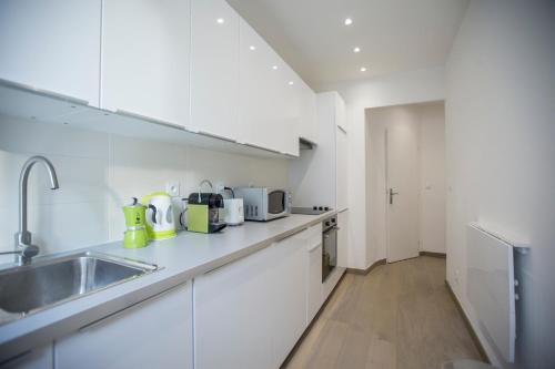 une cuisine avec des armoires blanches et un évier dans l'établissement Le Carré D'Or by Connexion, à Cannes