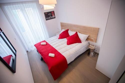 - une chambre dotée d'un lit rouge et blanc avec des oreillers rouges dans l'établissement Le Carré D'Or by Connexion, à Cannes