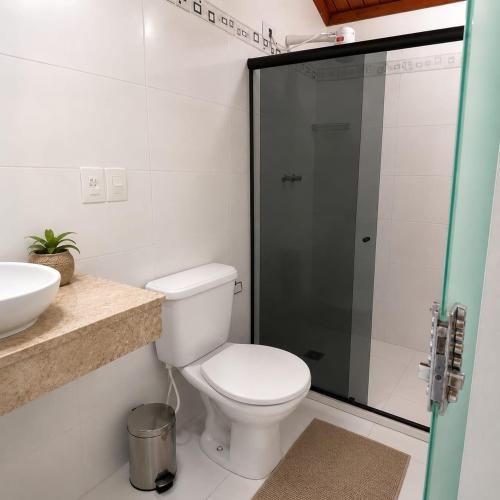 a bathroom with a toilet and a glass shower at Pousada Villa Grauçá in Morro de São Paulo