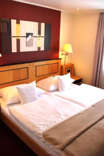 a large bed with white sheets and pillows at Hotel Riezler Hof in Riezlern